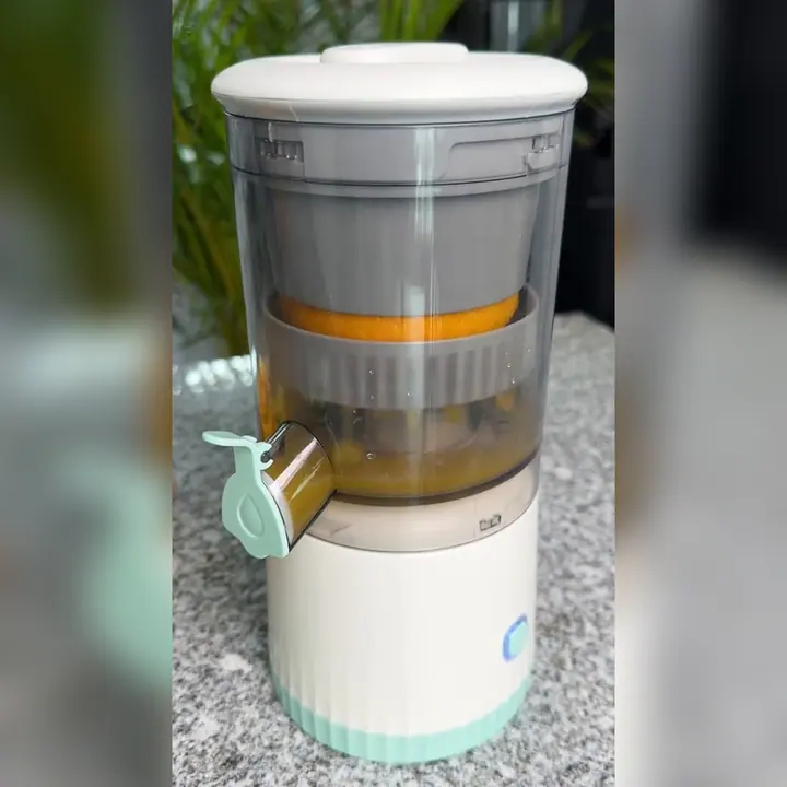 Exprimidor portátil exprimiendo una naranja sobre una encimera
